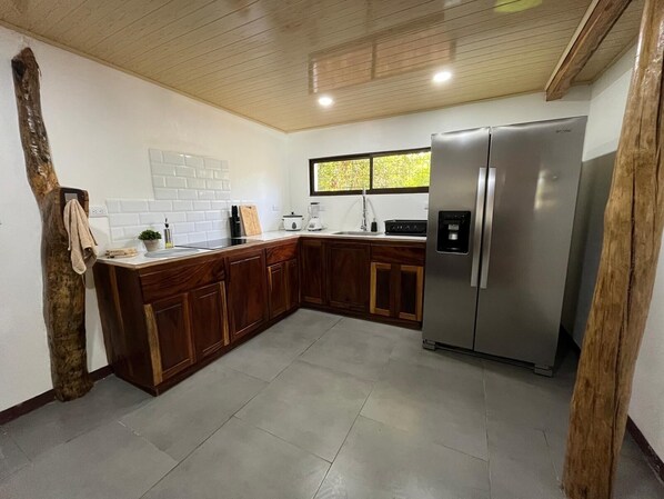 Una cocina moderna con armarios de madera, un refrigerador de acero inoxidable y un ventanal con vistas a la vegetación.