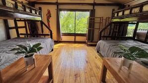 Ein Zimmer mit zwei Etagenbetten, Holzboden, einem Fenster mit Blick auf Grünflächen und einer Leiter.