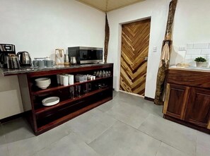 A kitchen with a microwave, coffee maker, and shelves with dishes and glasses.