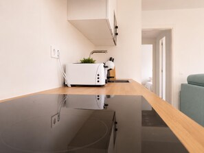 A modern kitchen with a black countertop, a white toaster, and a small potted plant.