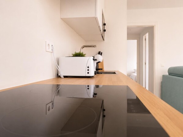 A modern kitchen with a black countertop, a white toaster, and a small potted plant.