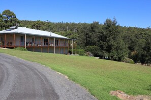 A two-story house with a balcony, surrounded by a grassy area and trees. - The Homestead -Discover Your Perfect Rural Retreat (Woodstock)