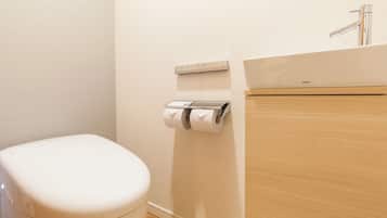A modern bathroom with a toilet, a toilet paper holder, and a sink.