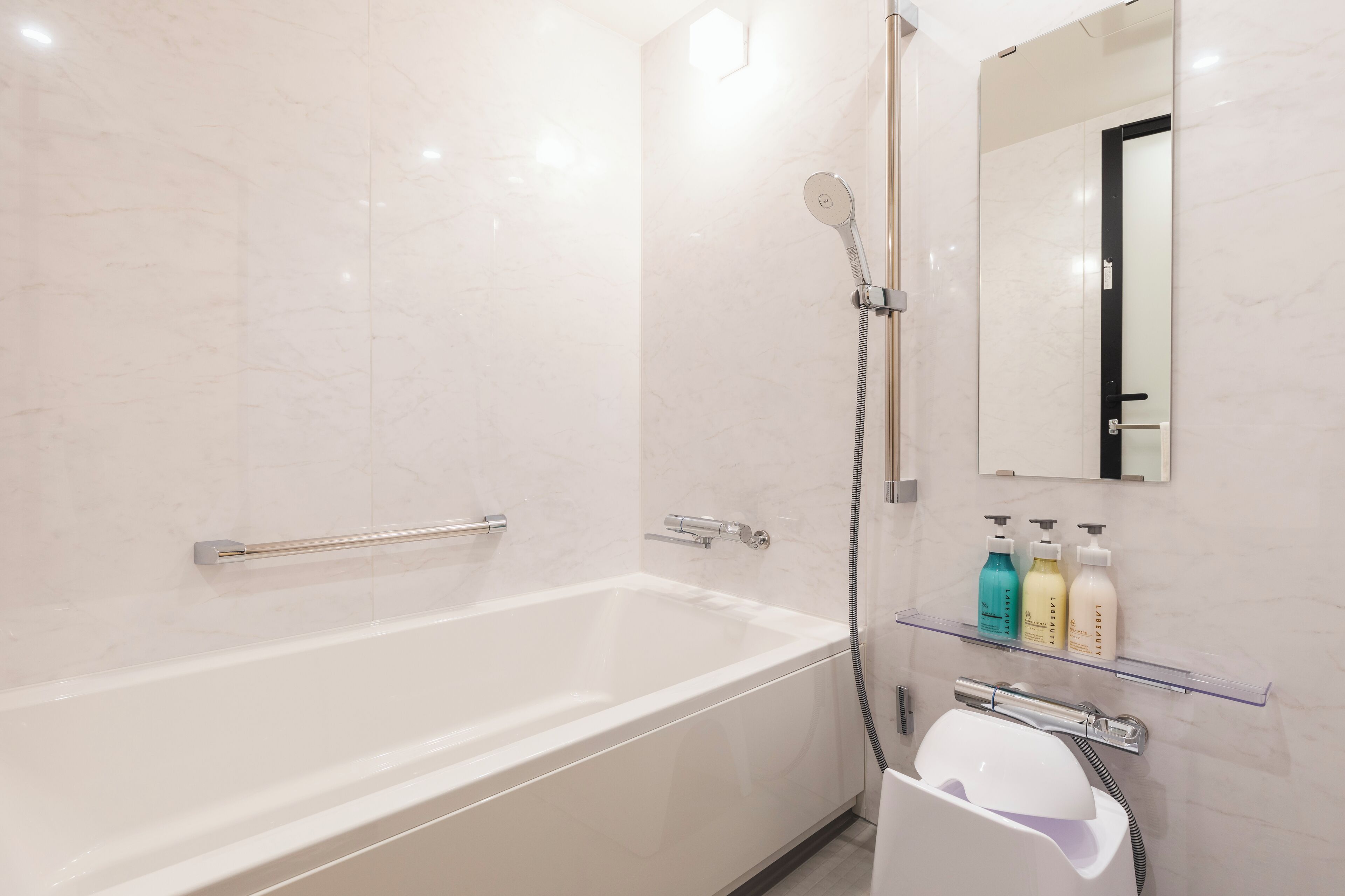 A modern bathroom with a white bathtub, a glass shower enclosure, and a mirror above the sink.