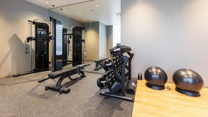 Ein modernes Fitnessstudio mit Krafttrainingsgeräten, einer Bank und Übungsbällen.