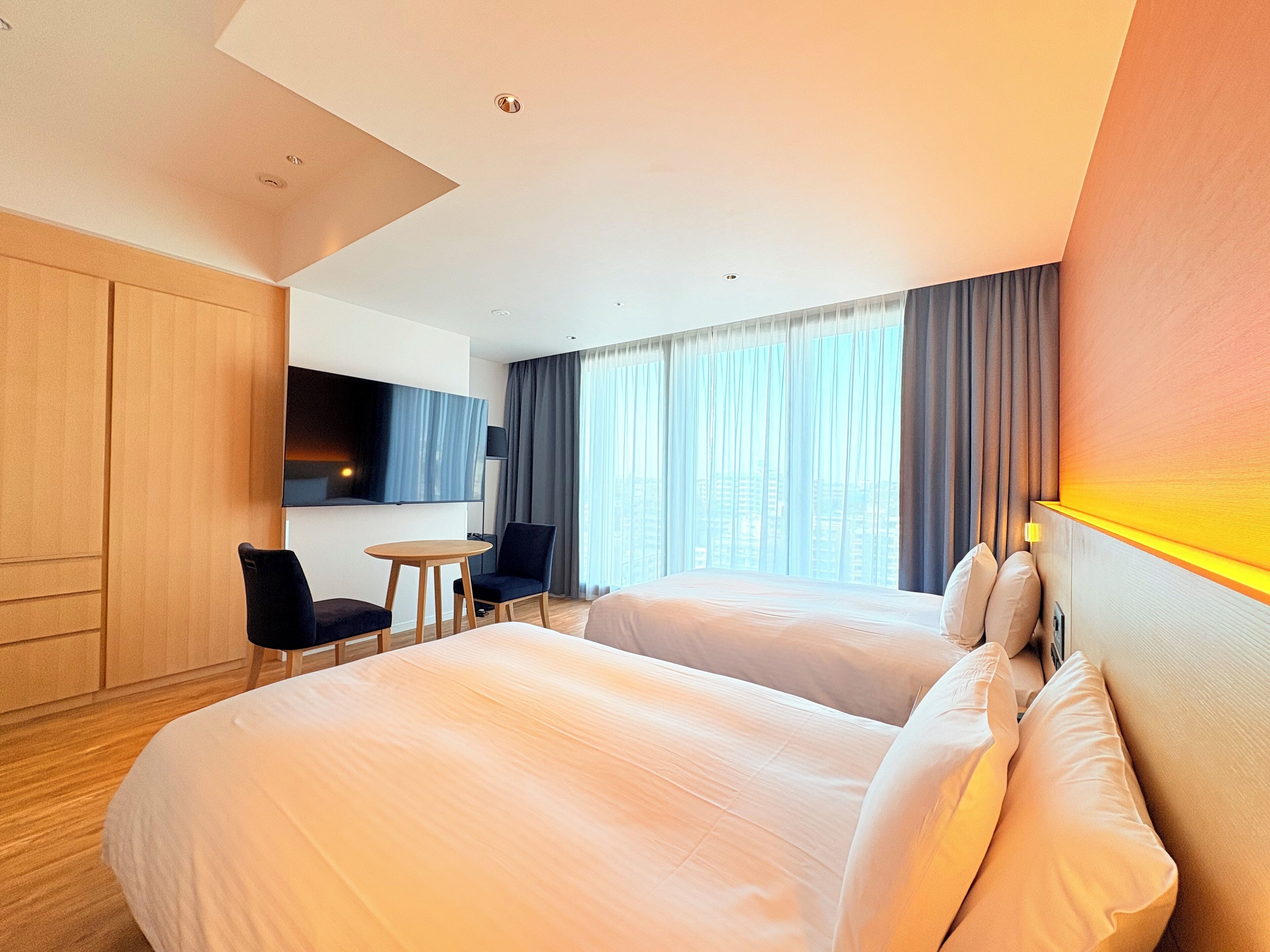 A hotel room with two beds, a TV, a desk, and a chair.