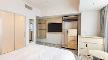 A hotel room with a bed, wardrobe, desk, and a TV.
