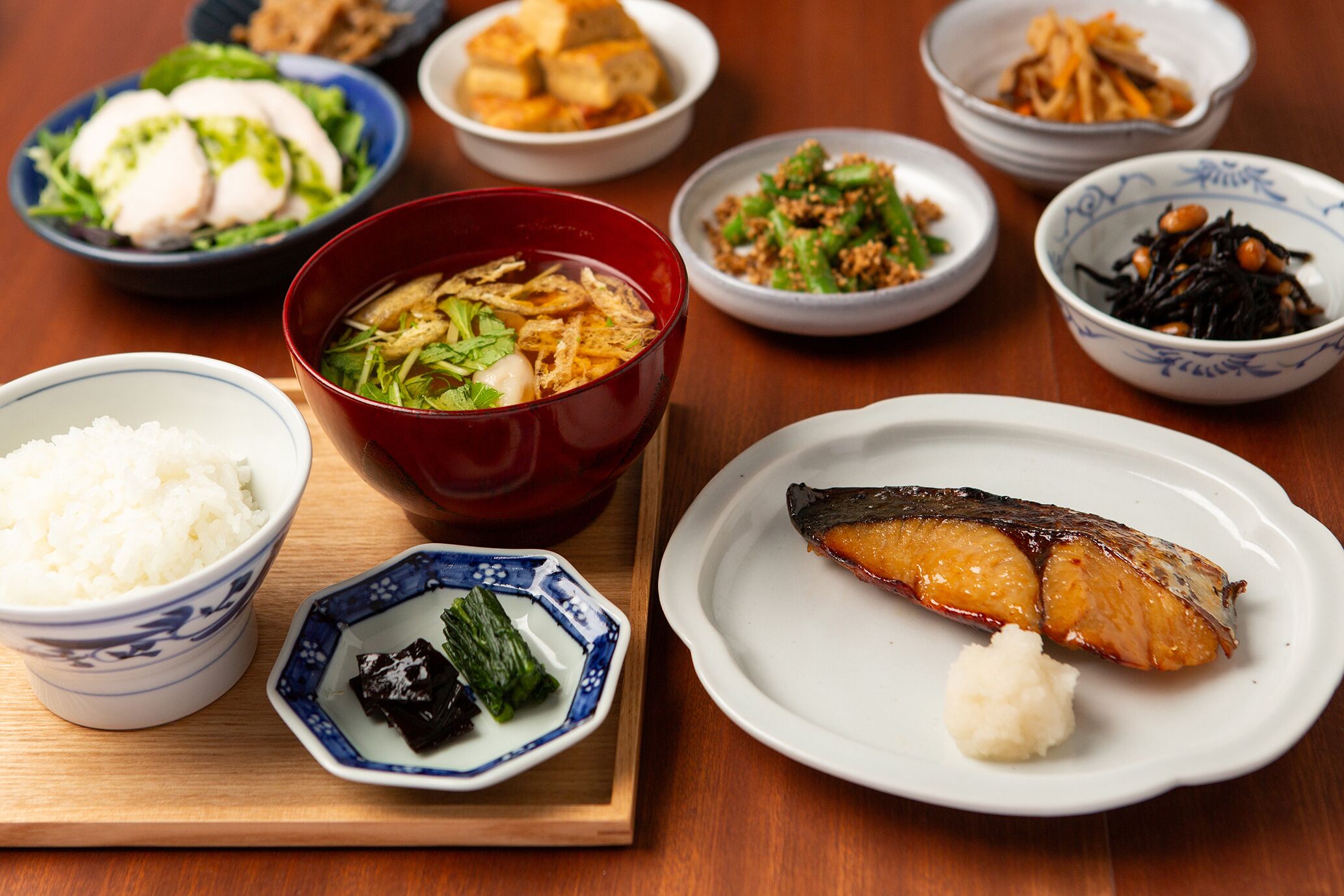 A variety of dishes including fish, rice, and vegetables on a wooden table.