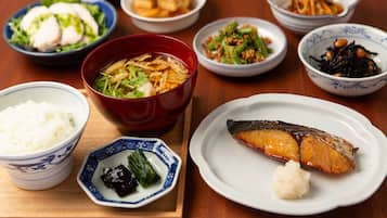 A variety of dishes including fish, rice, and vegetables on a wooden table.