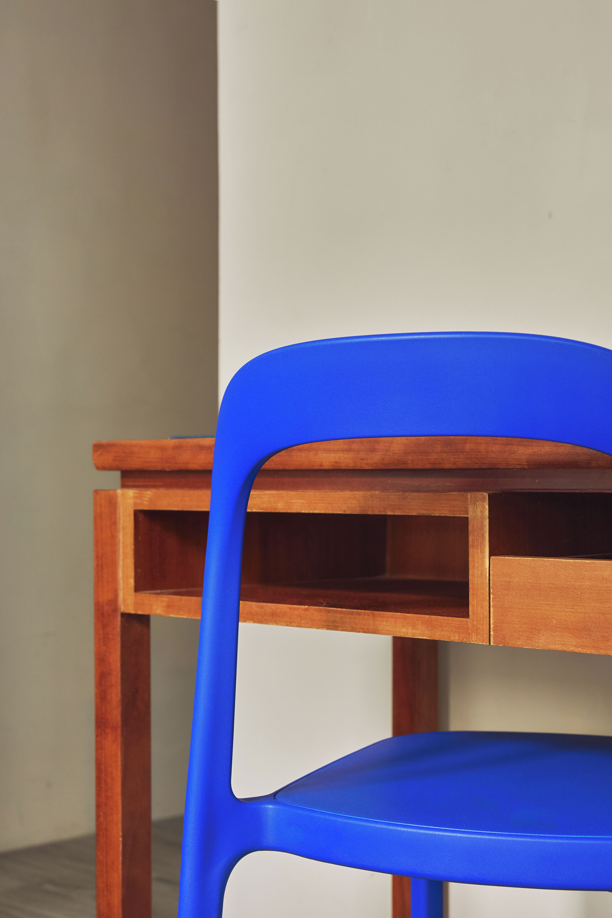 A blue plastic chair with a wooden table.