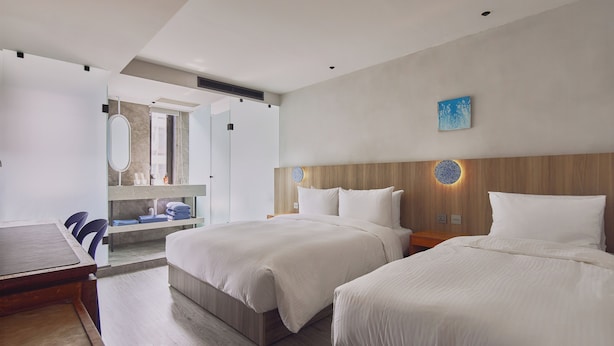 A modern hotel room with two beds, a wooden headboard, a large mirror, and a small table. - The Blue By Just Inn (Taipei)