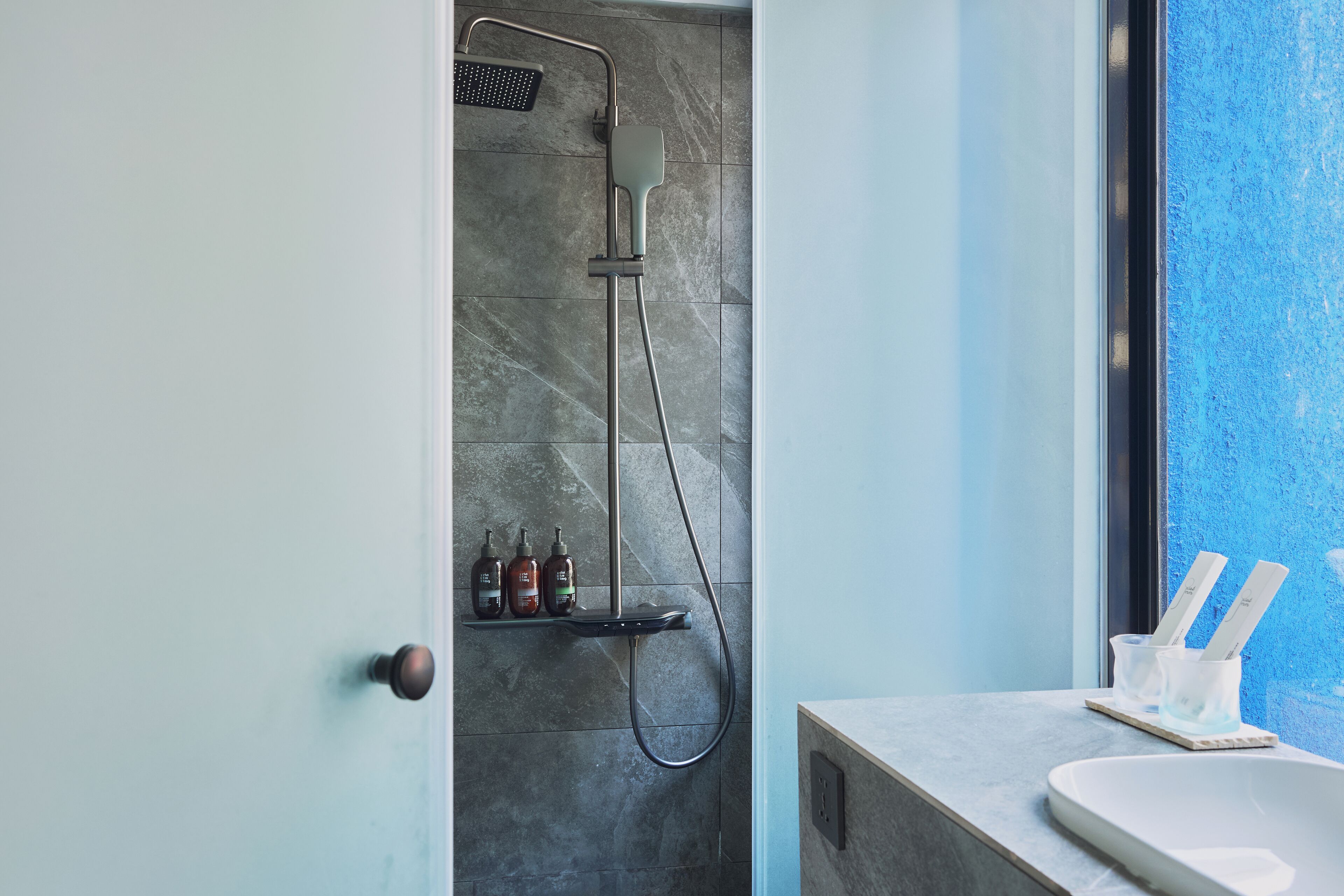 A modern bathroom with a shower, a sink, and a window.