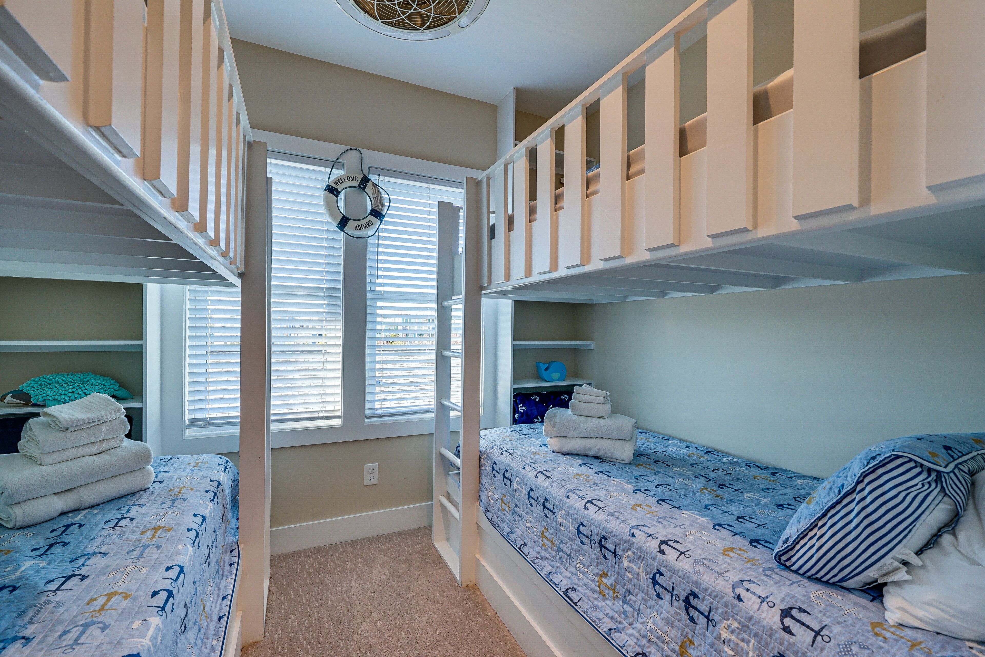 A bedroom with bunk beds, a window with blinds, and a door with a circular decoration.