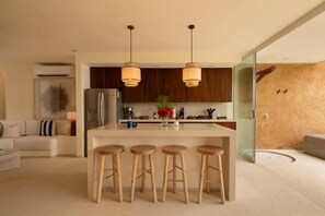 Una cucina moderna con isola centrale, sgabelli in legno e illuminazione a sospensione.