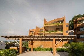 Un edificio moderno con numerosi balconi, una galleria coperta e aree verdi circostanti.