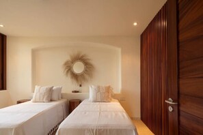 A bedroom with two beds, a wooden wardrobe, and a wall-mounted mirror.