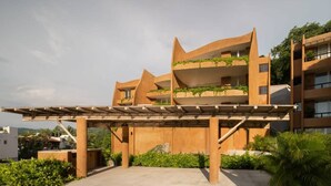 Um edifício moderno com várias varandas, uma galeria coberta e áreas verdes.