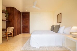 Un dormitorio con cama, una silla, un escritorio, un ventilador de techo y una puerta.