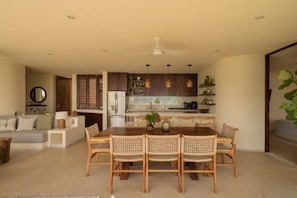 A modern kitchen with dark cabinets, a dining table with wicker chairs, and a ceiling fan.