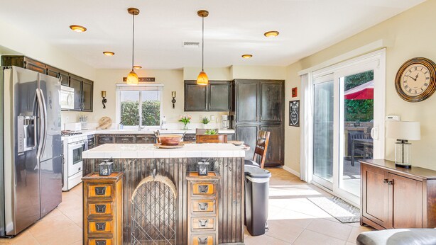 Una cocina moderna con una isla central, electrodomésticos de acero inoxidable e iluminación colgante.