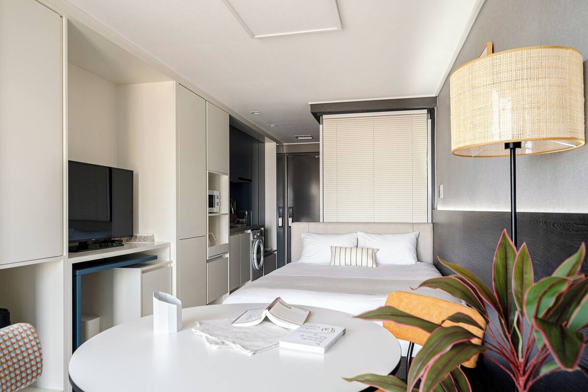 Ein modernes Hotelzimmer mit Bett, Nachttisch, Lampe und Fernseher.