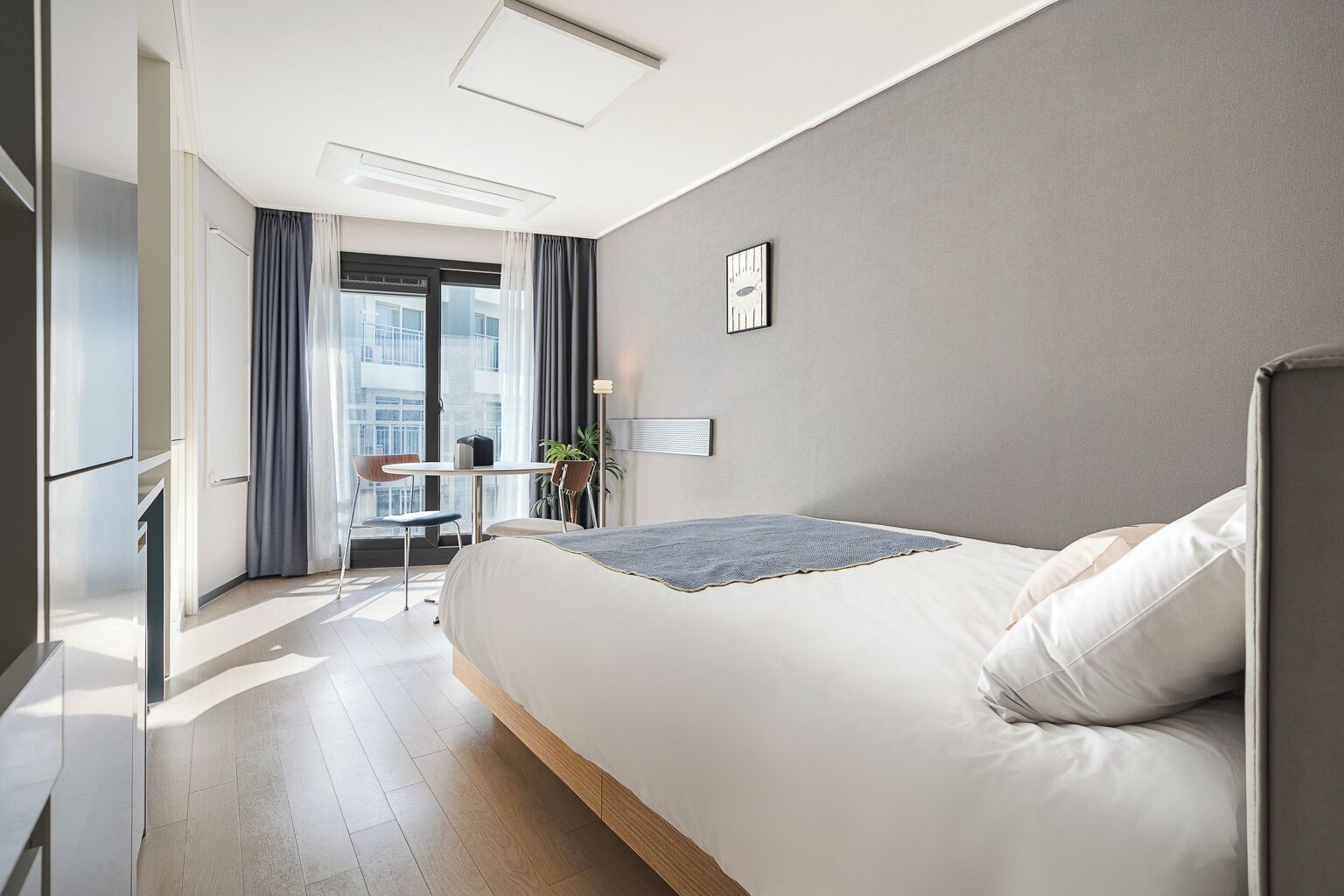 A modern hotel room with a large bed, a desk, and a view of the city.