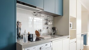 A modern kitchen with a built-in washing machine, stainless steel appliances, and a microwave.