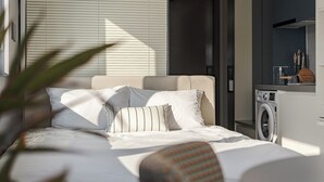 A modern bedroom with a bed, a washing machine, and a small table.
