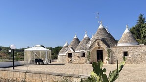 Ein traditionelles Steinhaus mit mehreren kegelförmigen Dächern und einer überdachten Außenbestuhlung.
