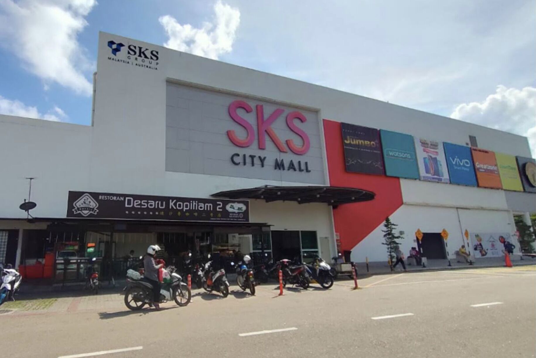 A building with a large 'SKS City Mall' sign, a restaurant named 'Restoran Desaru Kopitiam 2', and several motorcycles parked in front.