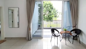 Een ruime kamer met balkon, een tafeltje met stoelen en een potplant.