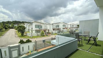 Houses line the street with large windows and flat roofs, featuring balconies with artificial grass.