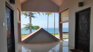 A hotel corridor with a view of the ocean and palm trees. - Pura Vida Varkala (Varkala)