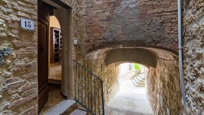 Un étroit couloir en pierre, agrémenté d’une rambarde métallique, mène à un escalier. Une porte portant le numéro 15 est visible sur la gauche.