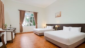 Camera d'albergo con due letti, una scrivania e una finestra con tende.
