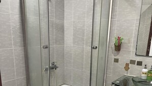A corner shower enclosure with a glass door, a white toilet, and a glass sink with a soap dispenser. - Dai Hong Hotel - by Bay Luxury (Ho Chi Minh City)