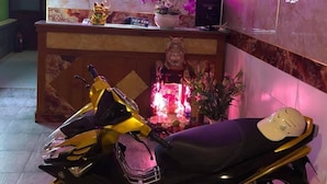A hotel reception desk with a neon sign, a motorcycle, and a Buddha statue. - Dai Hong Hotel - by Bay Luxury (Ho Chi Minh City)
