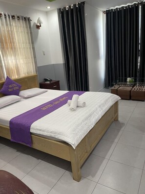 A hotel room with a wooden bed, a purple bedspread, and a pillow with "HOTEL DAI HONG" text. - Dai Hong Hotel - by Bay Luxury (Ho Chi Minh City)