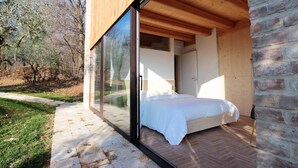Ein Schlafzimmer mit einem großen Glasfenster, einem Bett und einer Ziegelwand.