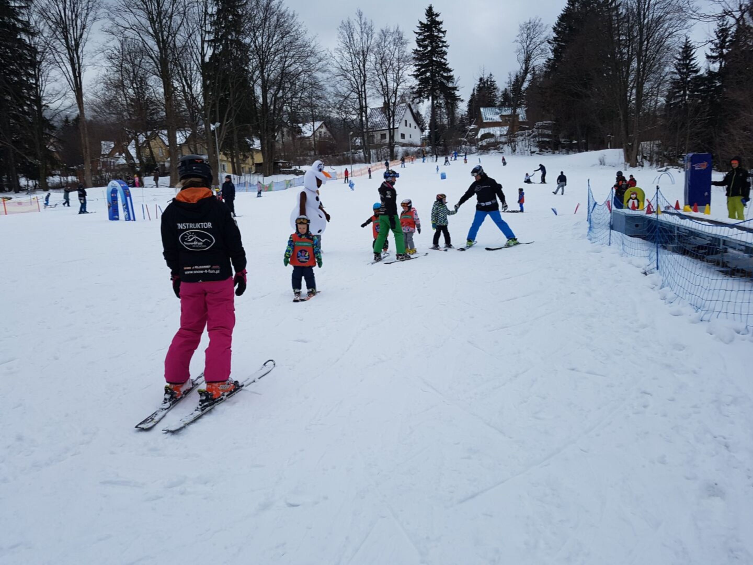 Una pista de esquí nevada con esquiadores y snowboarders.