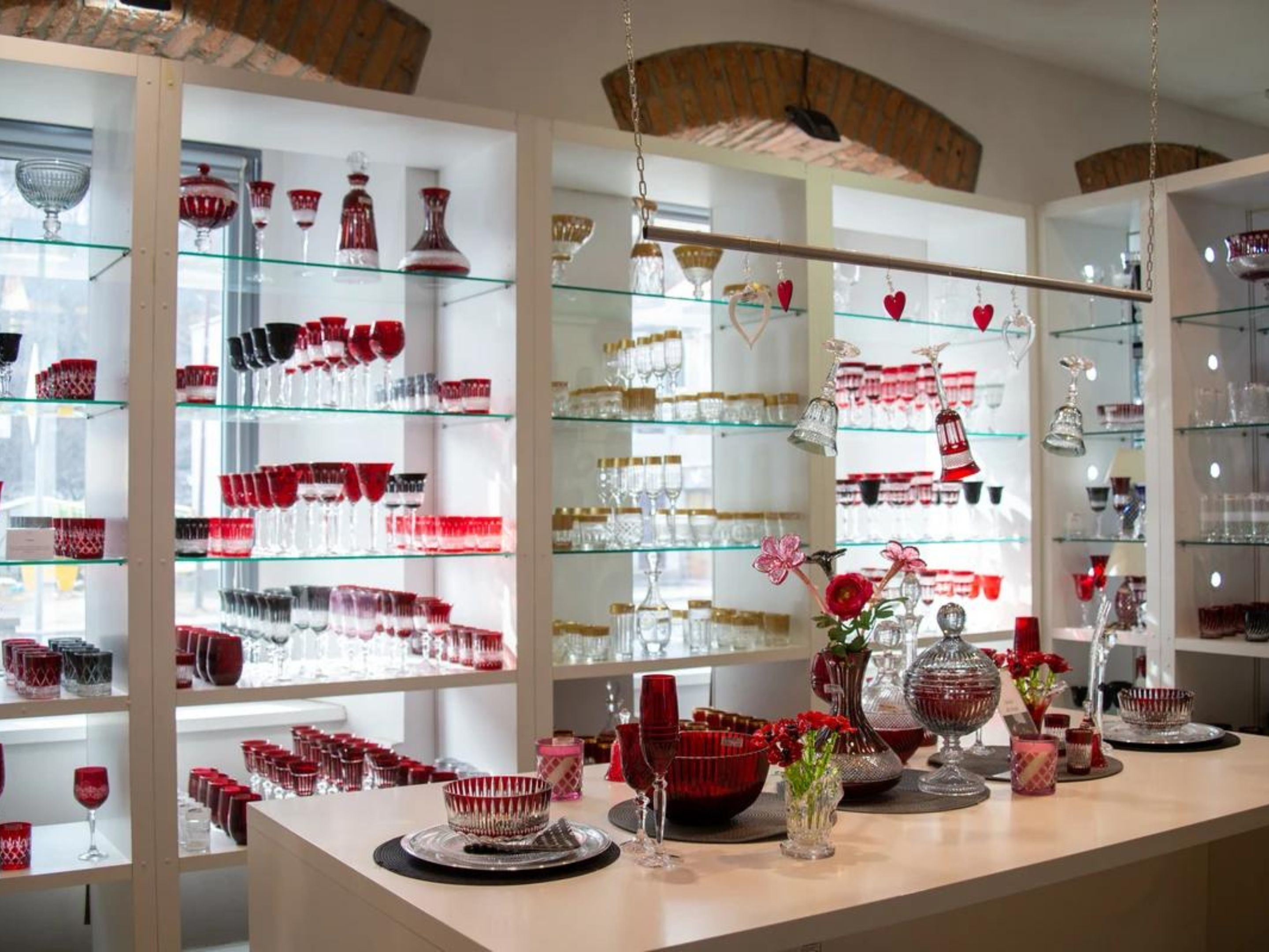 A well-lit store with glass shelves displaying various glassware and decorative items.