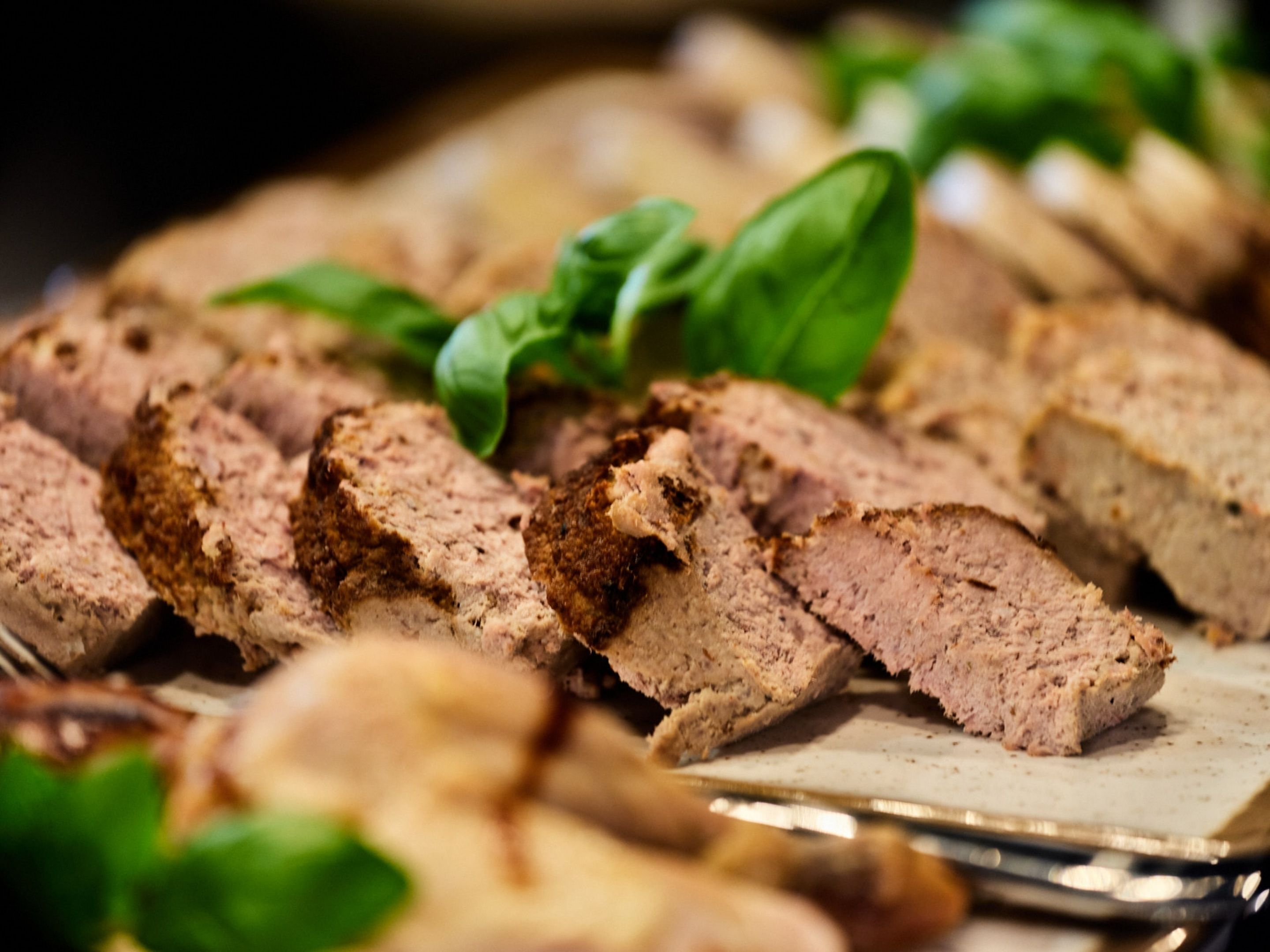 Sliced meat with herbs on a cutting board.