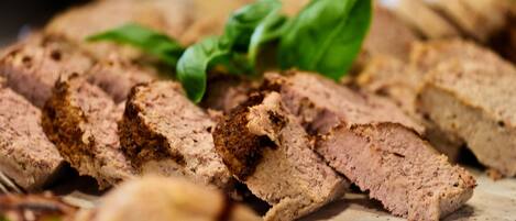Sliced meat with herbs on a cutting board.