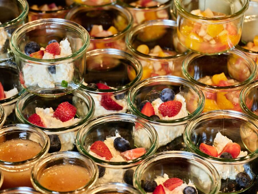 A variety of food items in glass containers, including fruits and desserts.