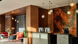 Un área de recepción moderna con un mostrador de madera, múltiples monitores de computadora y un gran cuadro abstracto en la pared.