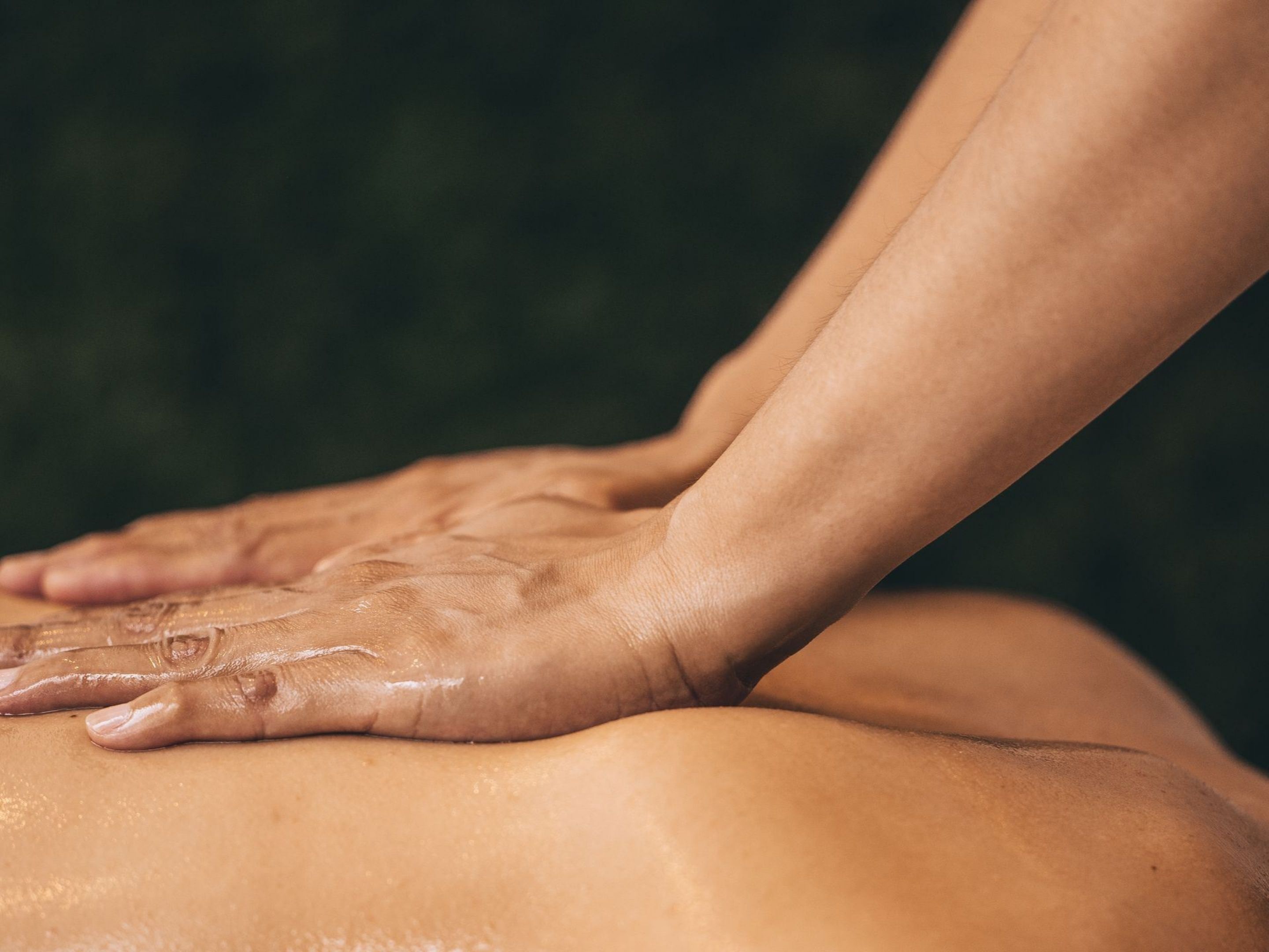 A close-up of hands performing a massage on a person's back.