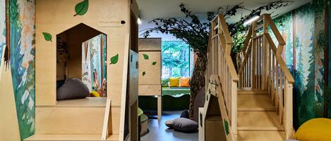 A children's play area with wooden structures, including a loft bed and a slide, and a staircase.