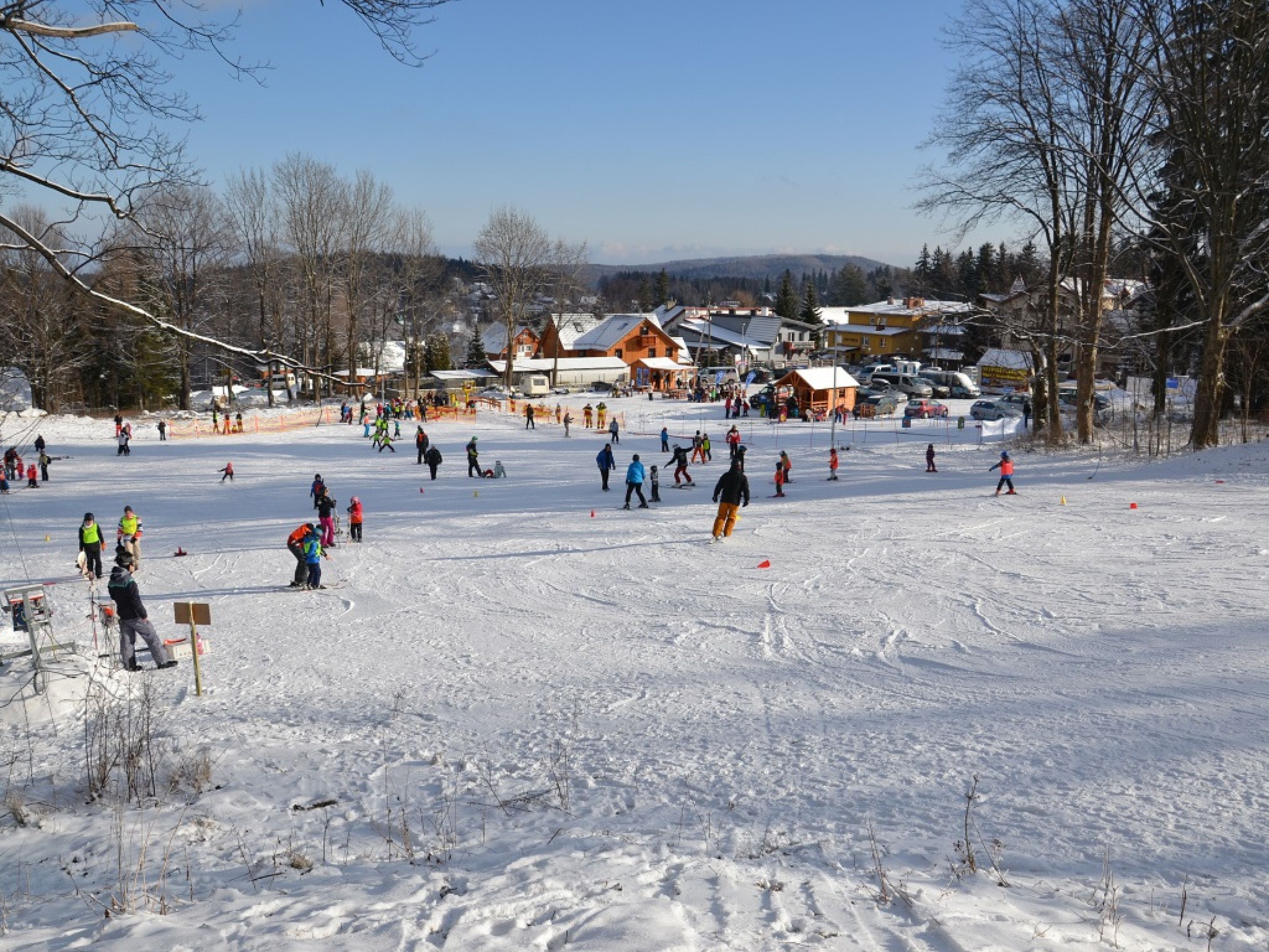 A snowy ski resort with multiple ski trails and a lodge in the background.