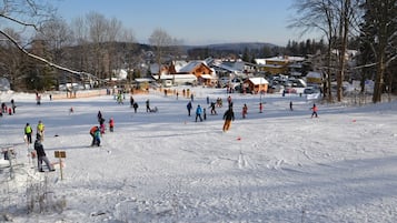 A snowy ski resort with multiple ski trails and a lodge in the background.