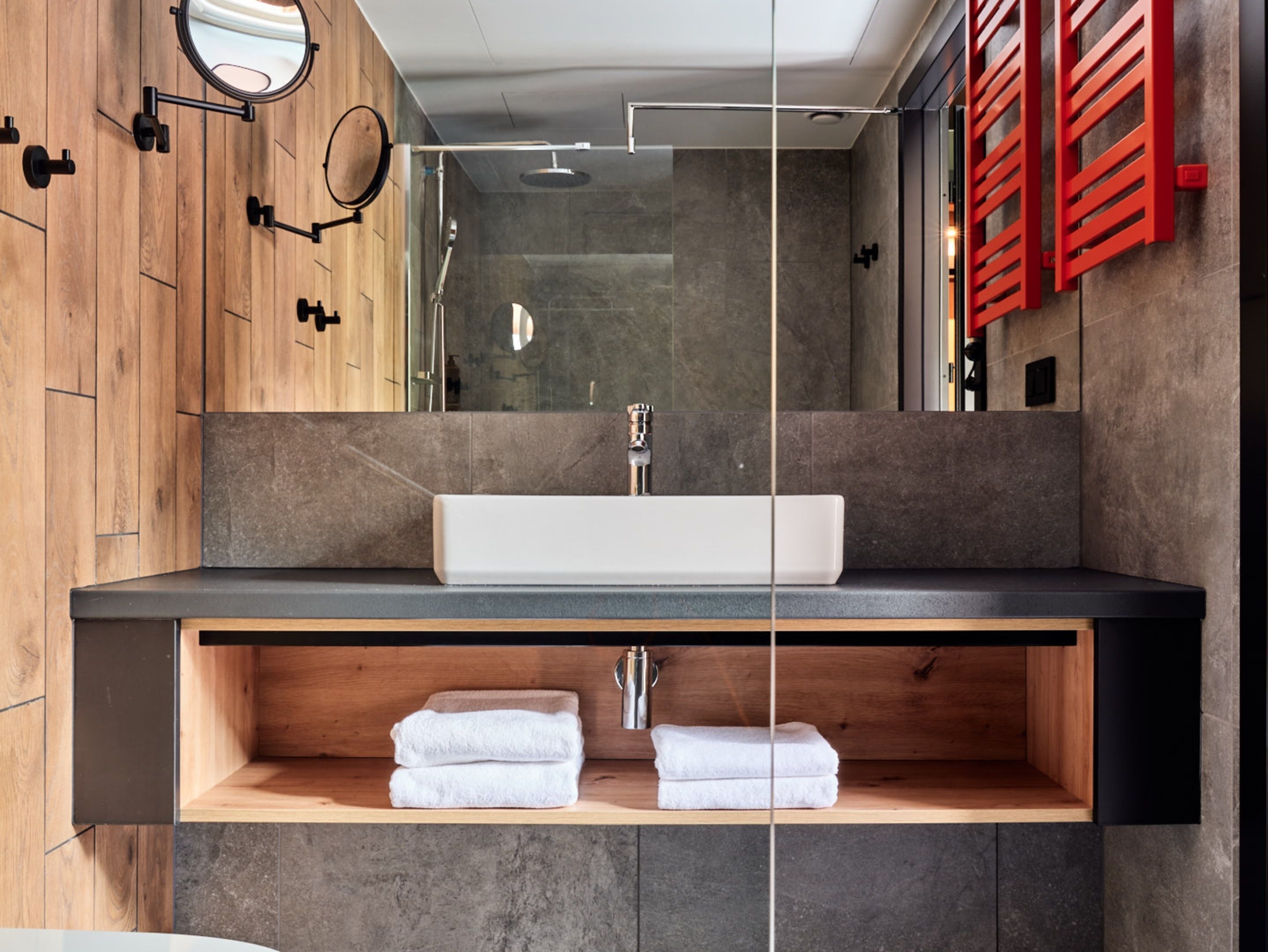 A modern bathroom with a wooden vanity, a large mirror, and a built-in shower area.